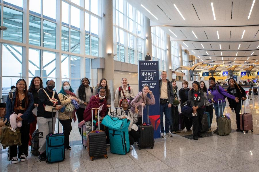 a group of students stand in an airport lobby